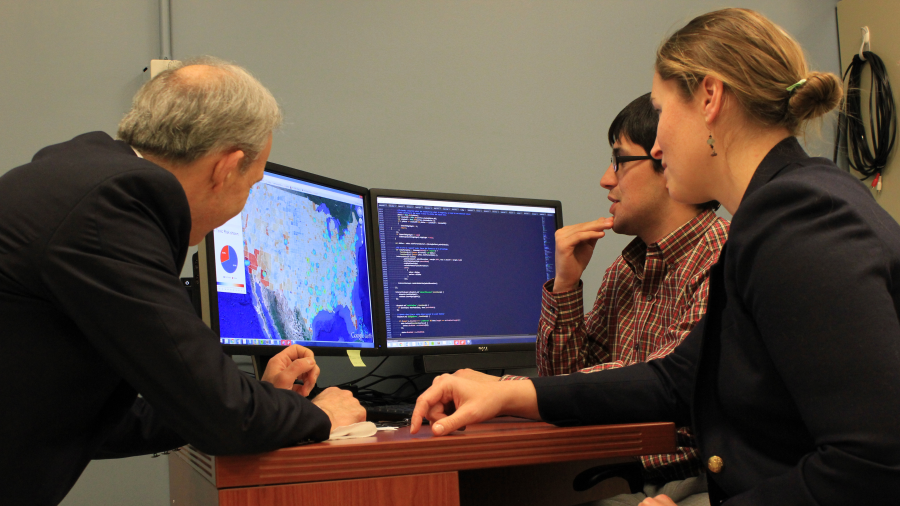  Three people looking at data at a computer screen