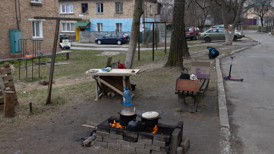 A pot over an open campfire in the yard of apartment buildings in an impoverished neighborhood