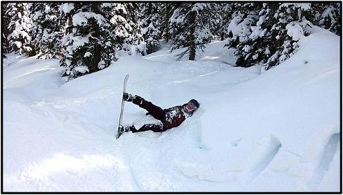 A person with a snowboard who has fallen into a snowdrift