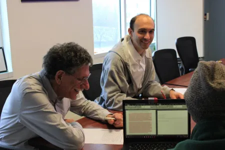 Dr. Schimel works with postdoctoral fellows seated around a table during a writing workshop
