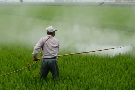 A man spraying herbicides over a field