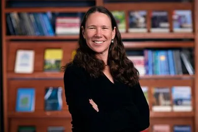 Dr. Epanchin-Niell stands in front of a book shelf 